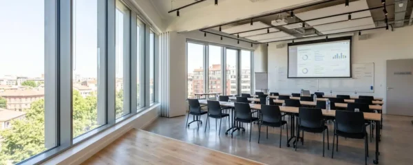 Salle de formation contemporaine à Toulouse avec grandes fenêtres laissant entrer une lumière naturelle abondante, tables et chaises modernes, écrans muraux affichant des graphiques analytiques flous